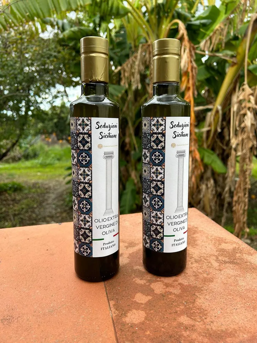 Due bottiglie di olio San Giuseppe fotografate tra le piante